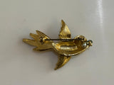 Gold bird-shaped brooch on a white background